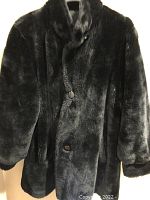 Black women's large faux fur winter coat front view showing button closure and plush texture.