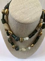 Front view of necklace displayed on beige fabric bust showcasing bead colors and materials.