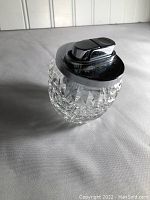 Front angle view showing the round cut glass body and chrome lighter top with lever igniter.