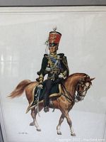 Close-up of framed print showing European soldier in green uniform on chestnut horse