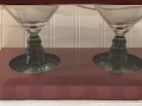 Two martini glasses with green Christmas tree stems in original box, viewed from front.