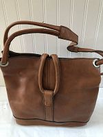 Front view of a large brown leather handbag with prominent stitched loop detail and double shoulder straps.