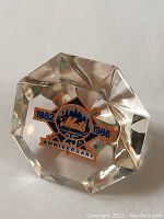 Faceted Lucite diamond-shaped paperweight with New York Mets 25th Anniversary logo from 1962 to 1986 inside.