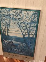 Photo showing the framed print depicting blue-toned stylized trees and flowers with mountainous landscape background