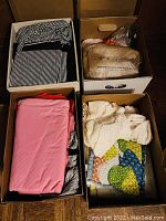 Photo showing four boxes filled with various pieces of fabric in different colors and patterns including stripes, solid pink, cream textured, and patchwork.
