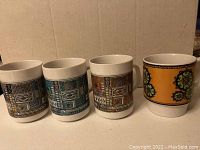 Photo showing four coffee mugs with various geometric designs in different colors and patterns.