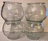 Four clear glass fishbowl style vases stacked two on two
