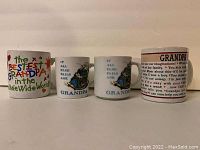 Photo of four grandpa-themed mugs lined up side by side on a surface showing various printed sayings and graphics.