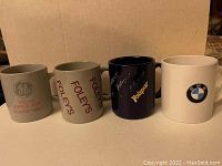Photo showing four brand advertising mugs: General Electric, Foley's, Valspar, and BMW in a row from left to right.