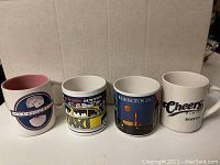 Photo of four souvenir coffee mugs from Atlantic City, New York, Washington DC, and Boston lined up on a surface.