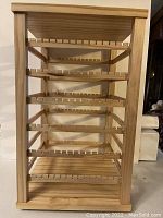 Full view of the wooden rotating earring holder showing the rectangular frame and five horizontal slotted racks designed for displaying earrings.
