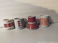 Four coffee mugs displayed side by side with various colorful themed prints