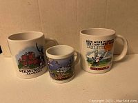 Photo showing three ceramic coffee mugs with southern US-themed designs representing Alabama, Mississippi, and Georgia.