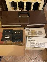 Photo showing several unused Maxell C45 audio cassette tapes, some in original Duplicator Series boxes and multiple brown plastic cassette cases.