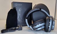 Photo showing Cowin E9 wireless noise canceling headphones in silver with black padded ear cups, adjustable headband, box, black soft pouch, USB charging cable, charging adapter, auxiliary cords and sound splitters.