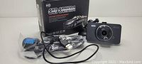 Photo showing the HD Car Camera driving video recorder with its original box, USB cable, and mounting accessories still in plastic packaging.