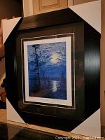 Framed and matted print in black frame with corner protectors, showing full artwork and frame size.