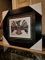 Photo showing the full framed art print "Thunderbird" with protective corner covers in place, depicting a large stylized bird in native art style.