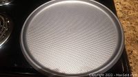 Top view of the round oven pizza pan with textured non-stick surface and raised edges.