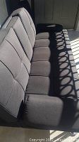 Side angled view of dark gray fabric sofa bed showing tufted seat and back cushions.
