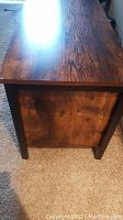 Close-up of the TV stand's side panel showing the wood grain and metal frame leg.