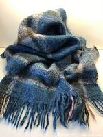 Full view of the folded mohair throw showing blue and green plaid pattern with fringed ends.