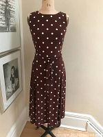 Front view of cinnamon-colored sleeveless dress with cream polka dots on mannequin.