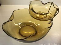 Large amber glass chip bowl with uneven collapsed edges holding smaller amber dip bowl on metal stand
