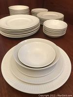 Multiple stacks of plates and bowls on wooden surface showing all five piece types together