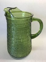Green textured glass pitcher with brick-like pattern, shown from the side with handle visible