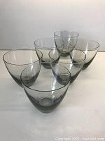 Six mid-century modern smoky grey lowball glasses arranged in groups showing their shape and color.