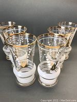 Front angle of the set of six vintage hand painted Lilly of the Valley bar glasses, showcasing the gold trim and floral design.