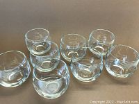 Top view of eight clear roly-poly scotch glasses arranged in a group showing their rounded shape and size.