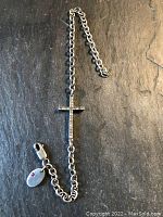 Full view of the sterling silver chain bracelet with crucifix and inscribed disc.