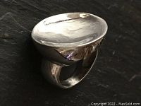 Close-up of sterling silver modernist ring showing rounded, solid concave top and band.