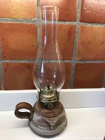 Photo showing full kerosene lamp with pottery base, brass fittings and glass chimney.