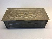 Top view of the vintage brass repousse cigarette case showing embossed floral design.