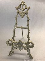 Front view of the ornate brass folding business card/picture easel showing full height and intricate design.