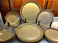 Full set displayed with dinner plates standing on holders in back, luncheon plates and cereal bowls stacked in front, all showing their consistent color and size.