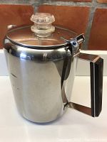 Side view of stainless steel coffee percolator showing the clear glass knob on the lid and teak handle on the right.
