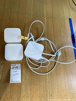 Three white Apple TV A1392 devices and two white power cords displayed on wood floor