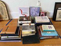 Multiple stacks of 27 assorted books including hardcover and paperback volumes with educational and informational topics.