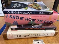 Stack of four cookbooks showing titles and authors on spines and covers for identification