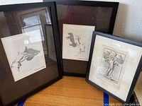 Three black-framed original artworks including two shadow hand illustrations and one religious figure print.
