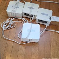 Four Sonos Connect second generation devices arranged on wooden floor with power cables wrapped around