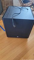 Front and side view of the Boston CS Sub10 subwoofer showing black textured finish and attached power cord.