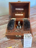 Open wooden case showing staking tool and organized steel punches and swage heads.