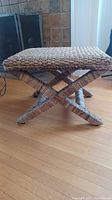 Full view of the wicker stool highlighting woven texture and crossed leg design