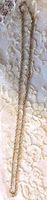 Photo of full length of twisted link chain displayed on lace fabric showing chain length and detail.