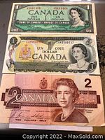 Front side of three Canadian banknotes: 1954 $1, 1973 $1, 1986 $2 bills showing portraits of Queen Elizabeth II.